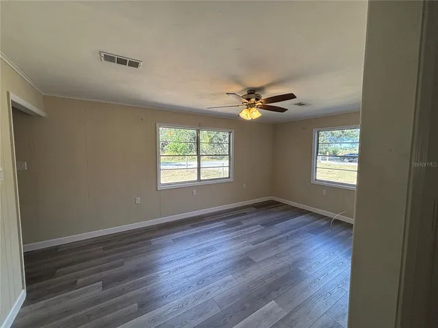 a view of an empty room with a window and wooden floor
