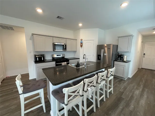 a kitchen with stainless steel appliances granite countertop a dining table chairs refrigerator and granite counter tops