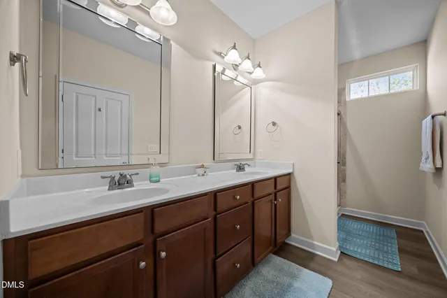 a bathroom with a double vanity sink and mirror with shower