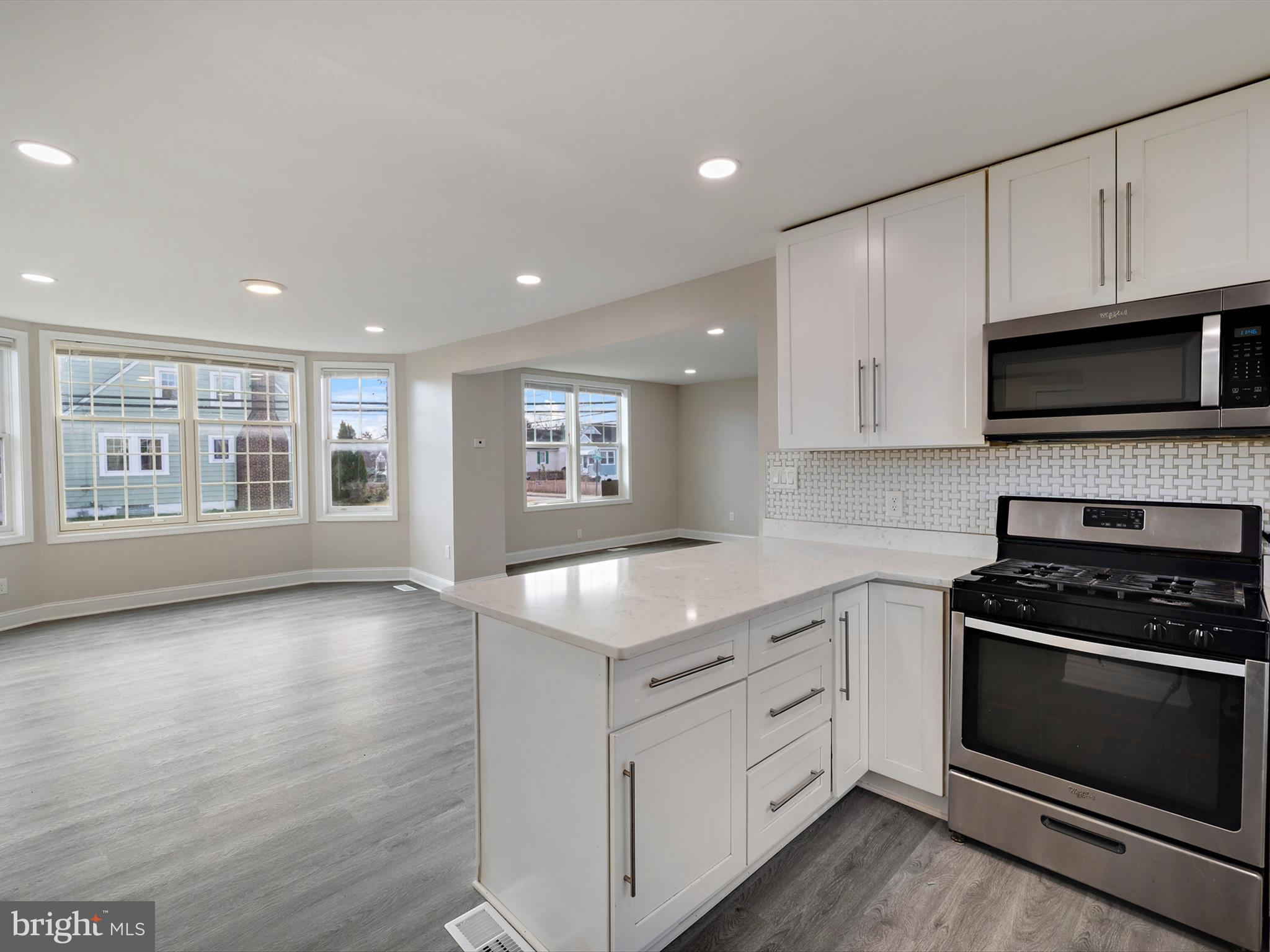 4129 5th Street Baltimore, MD 21225 - Photo 17 of 52 a kitchen with granite countertop a stove a sink and a microwave