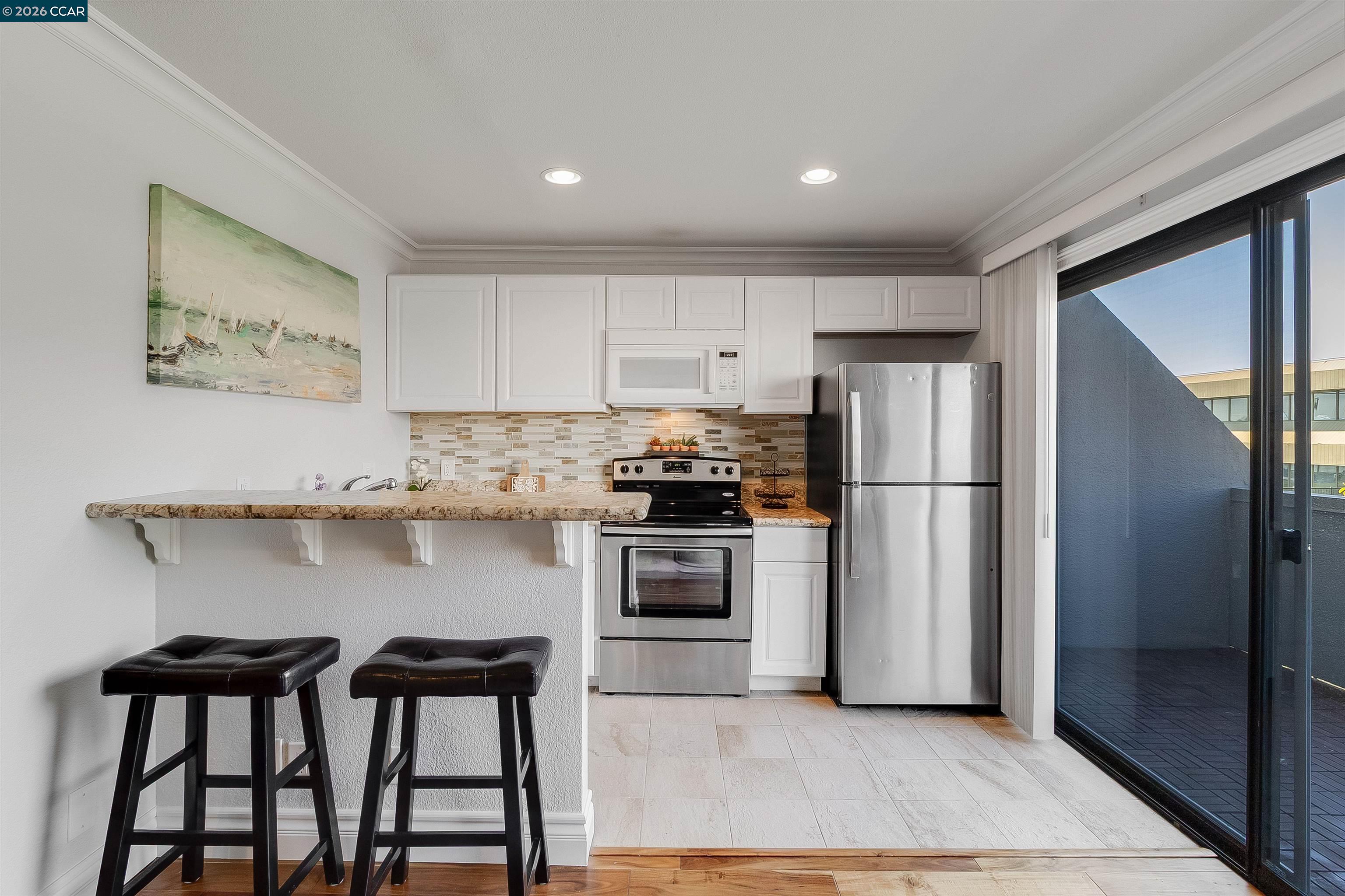 1 Embarcadero West, Unit 164 Oakland, CA 94607 - Photo 6 of 24 a kitchen with stainless steel appliances granite countertop a refrigerator a stove and a sink with wooden floor