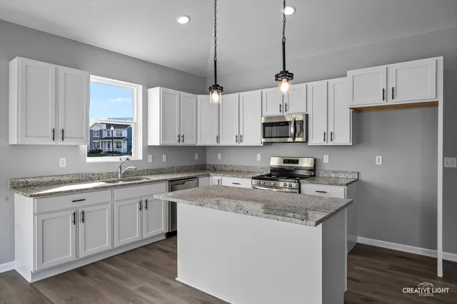 a kitchen with stainless steel appliances granite countertop a sink stove a refrigerator and white cabinets with wooden floor