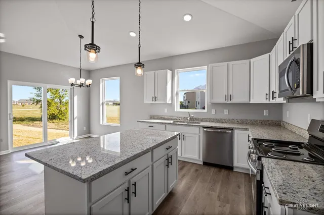 a kitchen with stainless steel appliances granite countertop a sink a stove a center island a window and cabinets