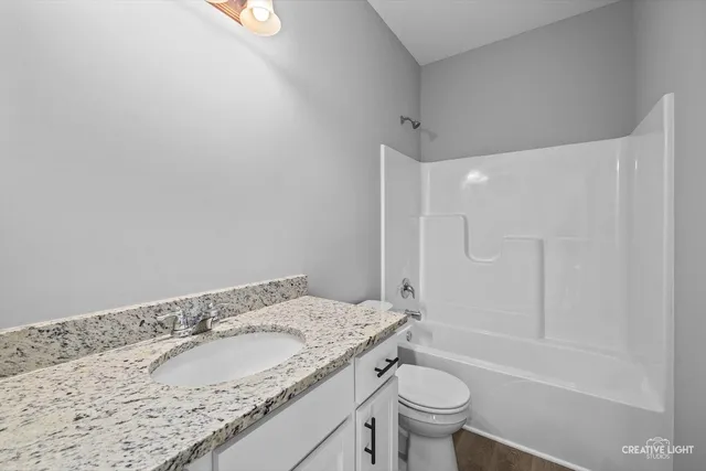 a bathroom with a granite countertop sink a toilet and shower