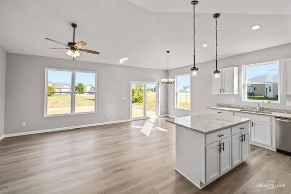 a kitchen with a stove a sink a window and chairs