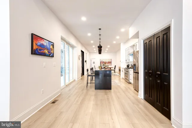 a kitchen with stainless steel appliances kitchen island granite countertop a stove a sink a dining table and chairs with wooden floor