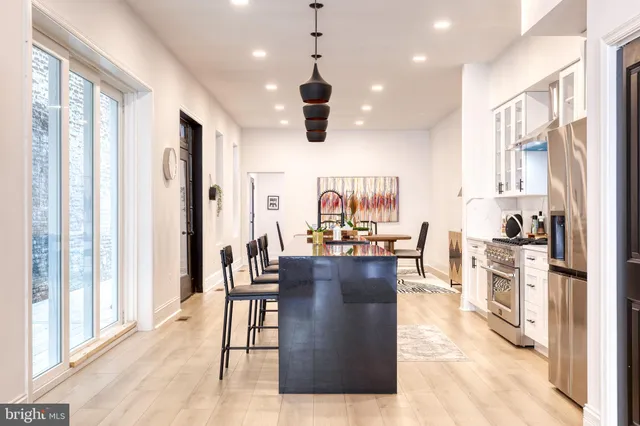 a kitchen with stainless steel appliances kitchen island granite countertop a stove a sink a refrigerator and chairs