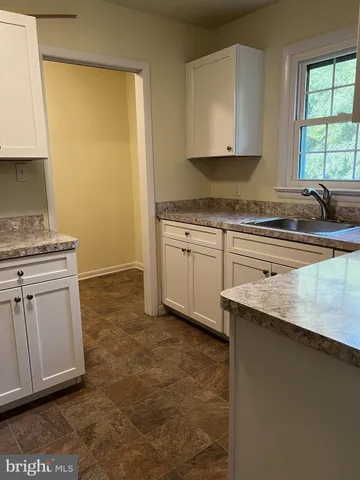 a kitchen with granite countertop a sink stove and cabinets