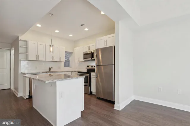 a kitchen with a refrigerator a stove top oven and wooden floors