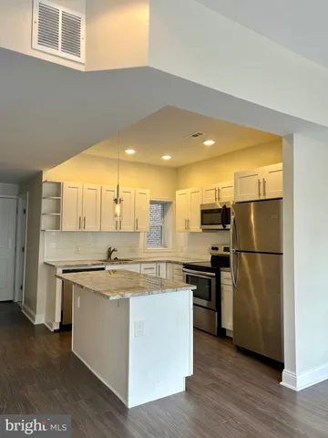 a kitchen with a sink a refrigerator and white cabinets