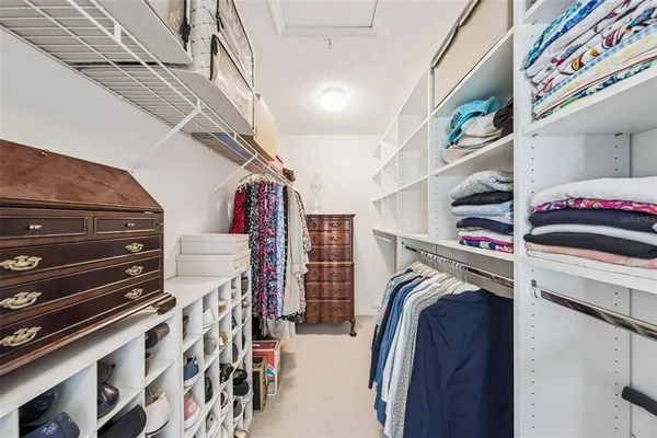 a view of walk in closet with clothes and shoes