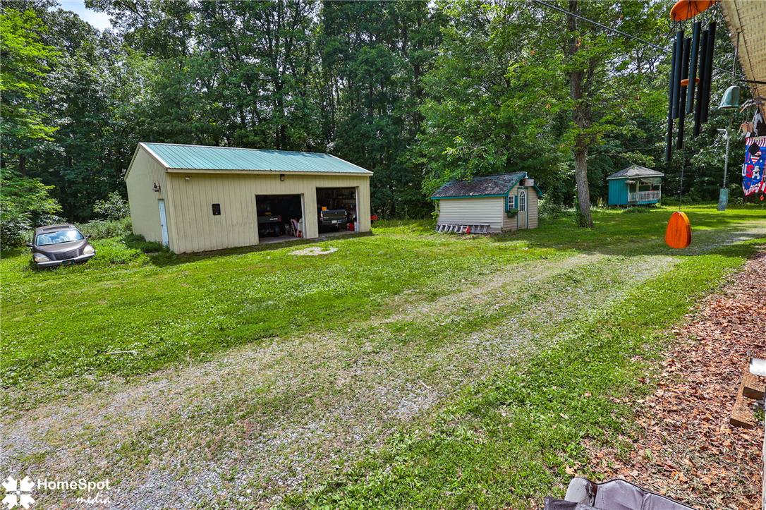 3795 Rhoades Road Kempton, PA 19529 - Photo 34 of 42 A spacious yard boasts multiple outbuildings and a functional garage, surrounded by mature trees.