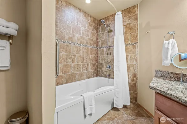 a bathroom with a granite countertop bathtub shower sink and mirror