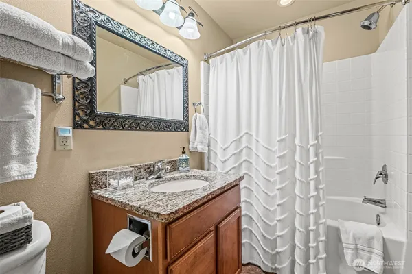 a bathroom with a granite countertop sink a mirror and a shower curtain
