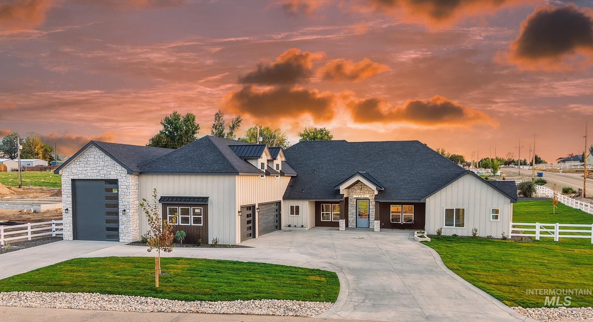 Modern farmhouse style home with driveway, a shingled roof, an attached garage, board and batten siding, and stone siding
