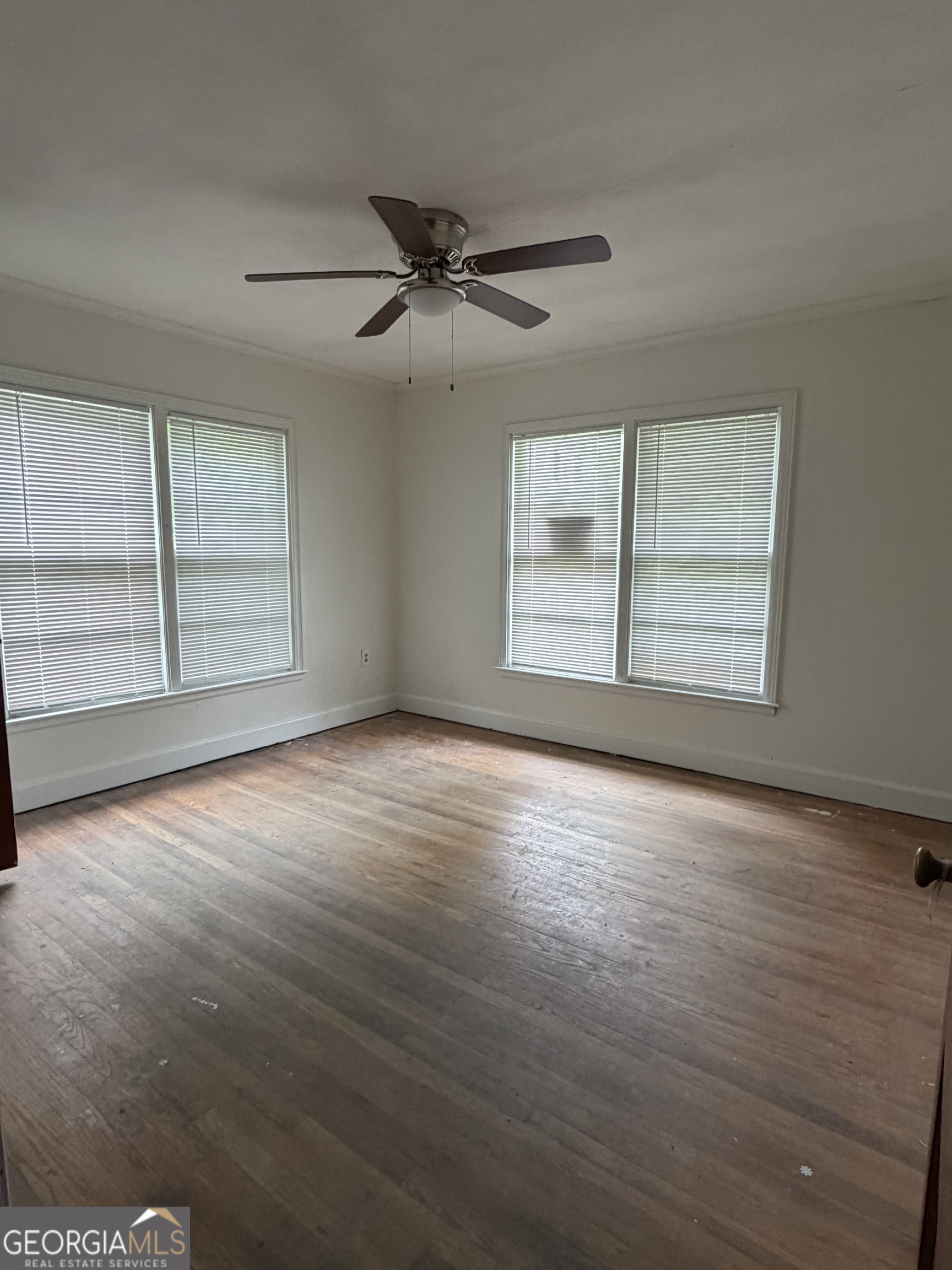 225 West Jessamine Street Fitzgerald, GA 31750 - Photo 22 of 39 an empty room with wooden floor fan and windows