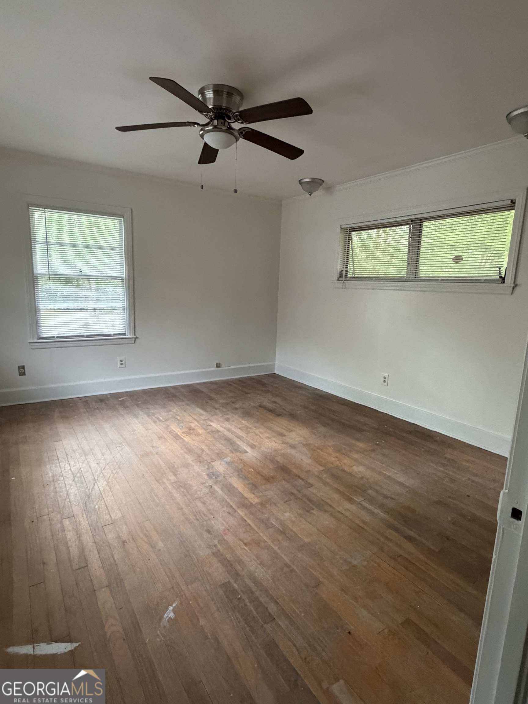 225 West Jessamine Street Fitzgerald, GA 31750 - Photo 26 of 39 an empty room with wooden floor fan and windows