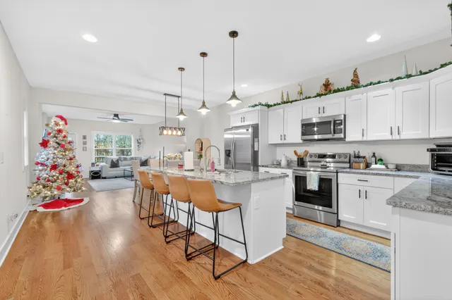a open kitchen with kitchen island a stove a sink dishwasher and a refrigerator with wooden floor