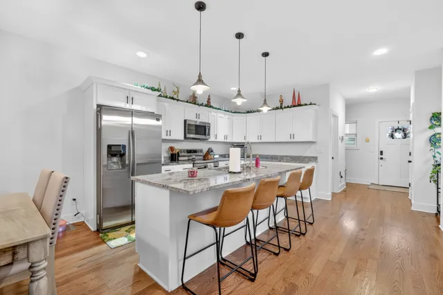 a kitchen with stainless steel appliances kitchen island a refrigerator and a wooden floor