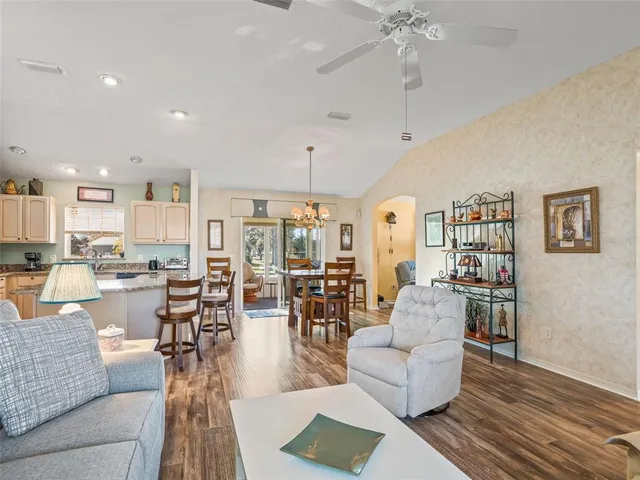 a living room with furniture kitchen view and a chandelier