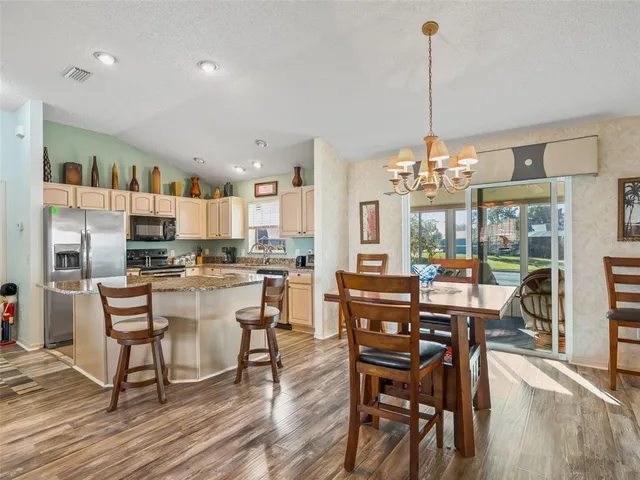 a view of a dining room and livingroom with furniture wooden floor a chandelier