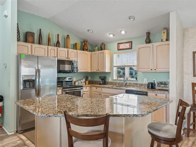 a kitchen with stainless steel appliances granite countertop a sink refrigerator and cabinets