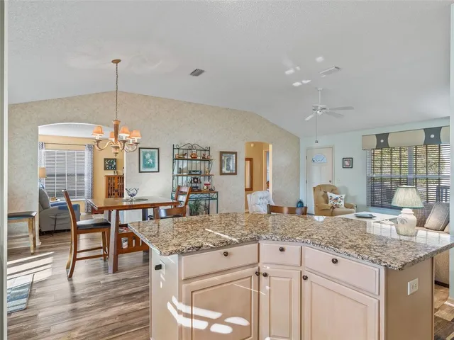 a kitchen with granite countertop a table chairs stove and wooden floor