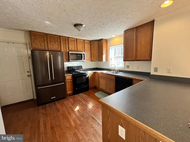 a kitchen with stainless steel appliances granite countertop a refrigerator a sink dishwasher and a stove