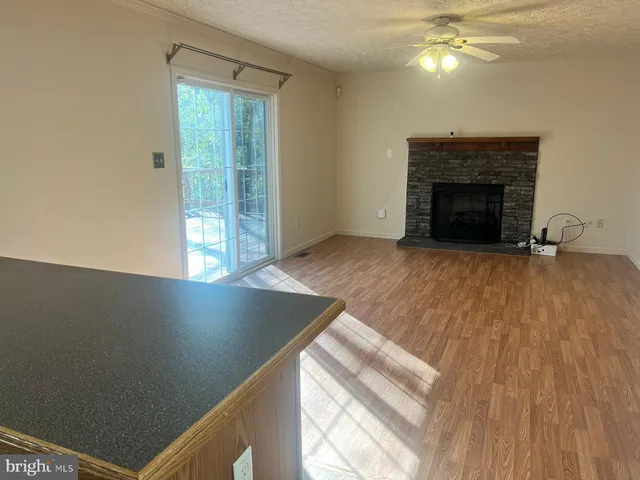 an empty room with wooden floor fireplace and windows