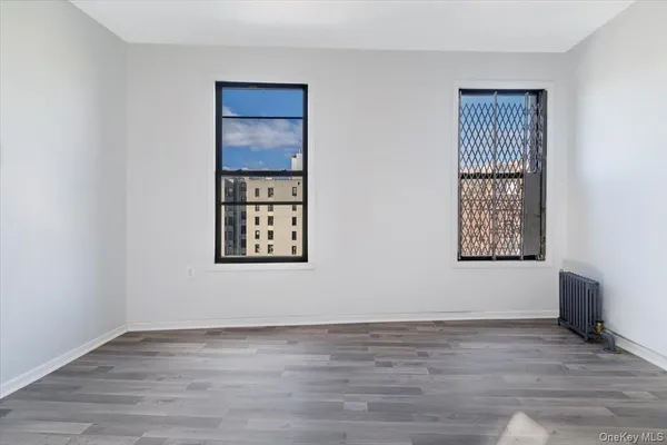 a view of an empty room with wooden floor and windows