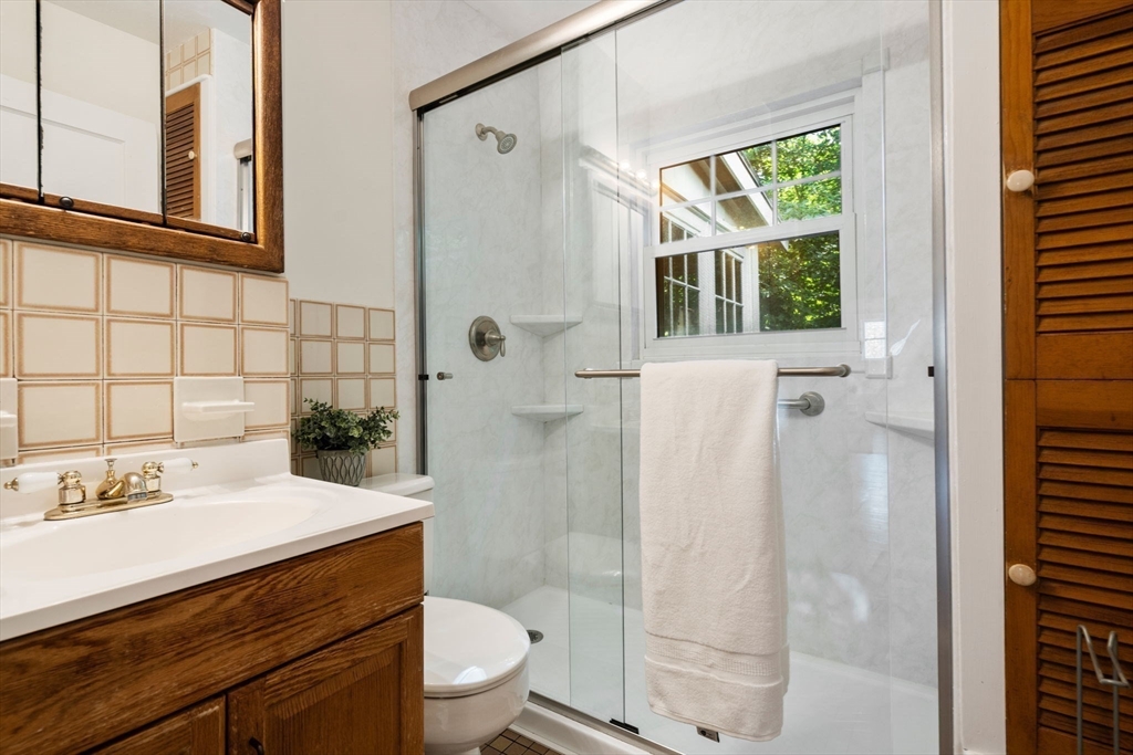 500 Washington Street, Unit 2 Brookline, MA 02445 - Photo 15 of 23 a bathroom with a sink a toilet a glass door a shower and a window