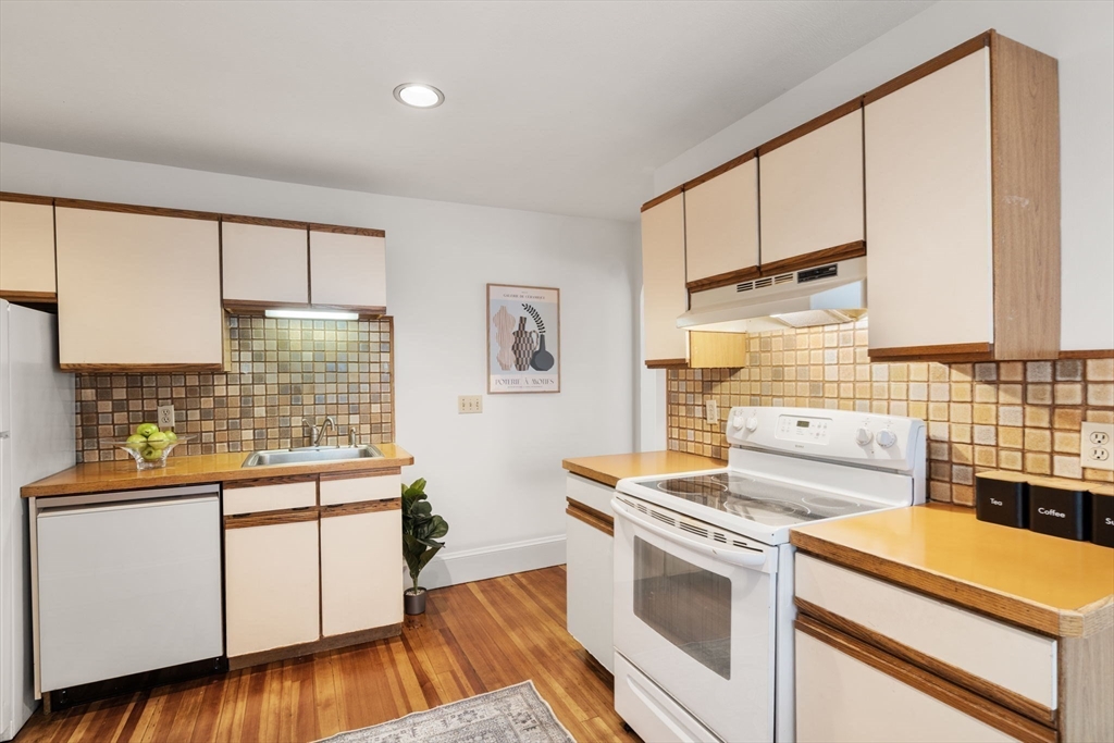 500 Washington Street, Unit 2 Brookline, MA 02445 - Photo 8 of 23 a kitchen with stainless steel appliances a stove a sink dishwasher and white cabinets with wooden floor