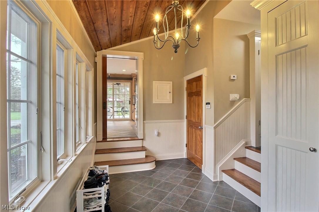 6715 Eagle Road Willoughby, OH 44094 - Photo 6 of 22 Entrance foyer featuring lofted ceiling, an inviting chandelier, dark tile floors, wooden ceiling, and crown molding