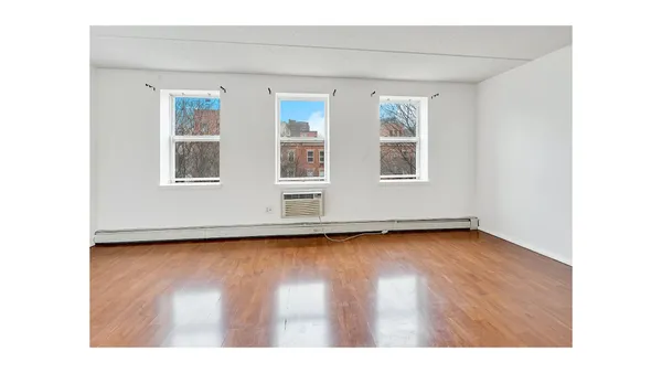 a view of an empty room with wooden floor and a window