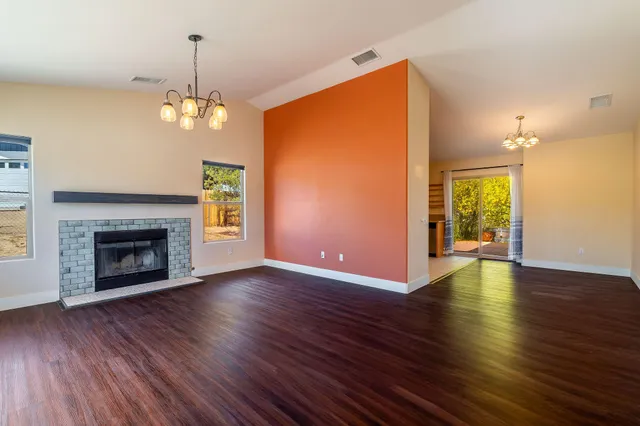 a view of a room with wooden floor fireplace and window