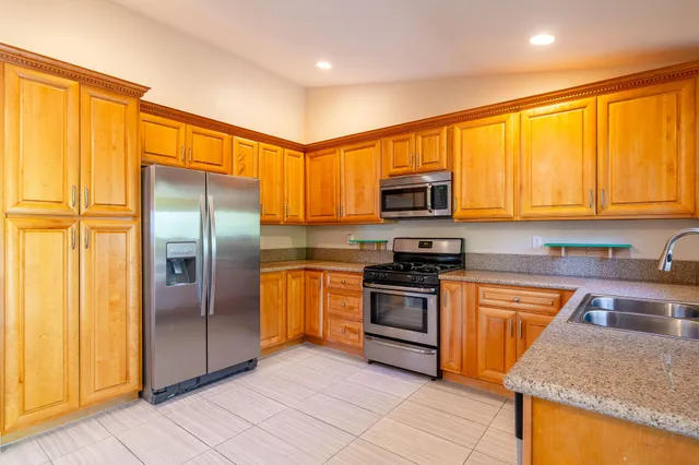 a kitchen with stainless steel appliances granite countertop a stove top oven a refrigerator and a sink