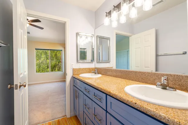 a bathroom with a granite countertop sink a mirror and a shower