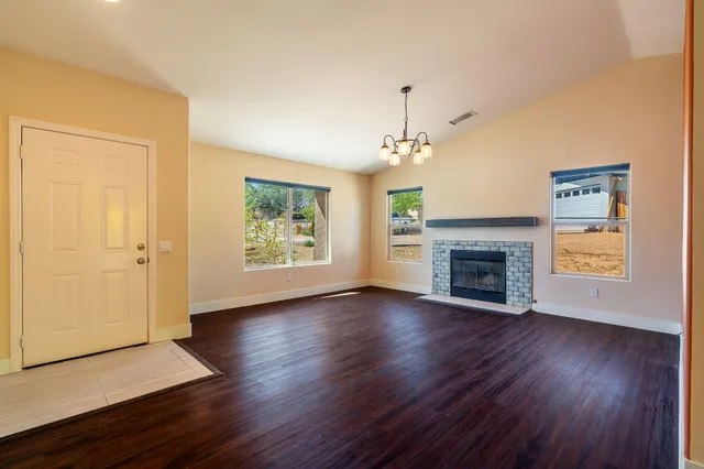 an empty room with wooden floor fireplace and windows