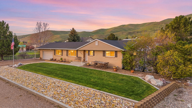 Single story home with a mountain view, a front yard, a garage, driveway, and brick siding