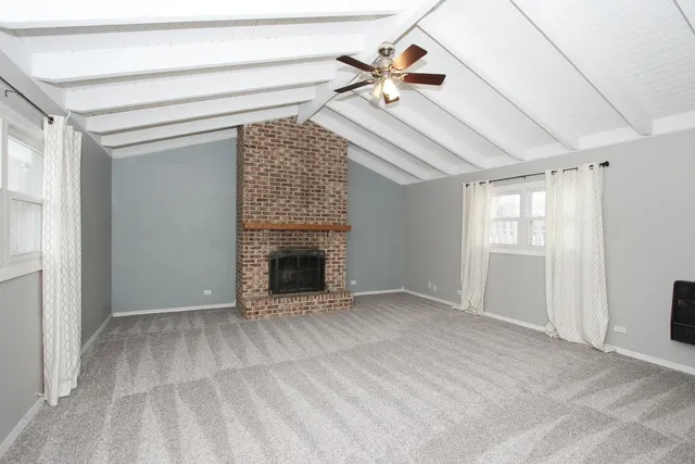 a view of an empty room with chandelier fan and fire place