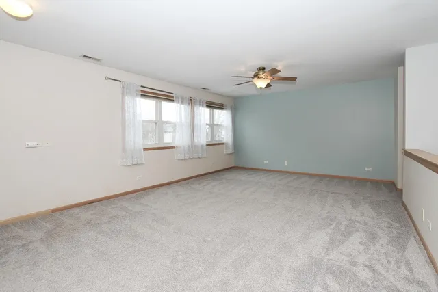 an empty room with windows and ceiling fan