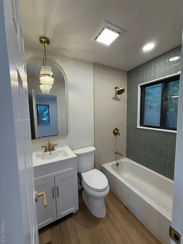 a bathroom with a toilet a sink a tub and mirror
