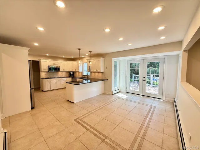 a large white kitchen with a large window and stainless steel appliances
