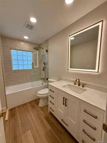 a bathroom with a granite countertop sink toilet tub and mirror