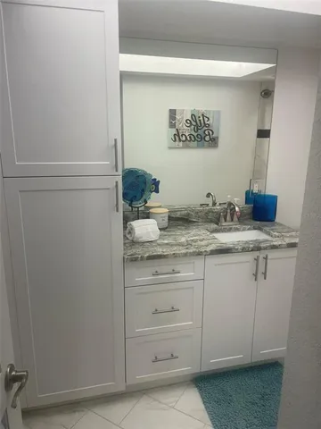 a bathroom with a granite countertop sink and a mirror