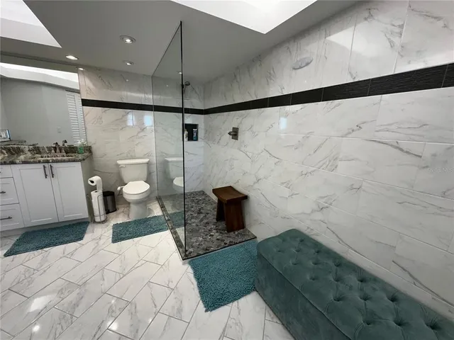 a bathroom with a granite countertop sink a toilet and a shower