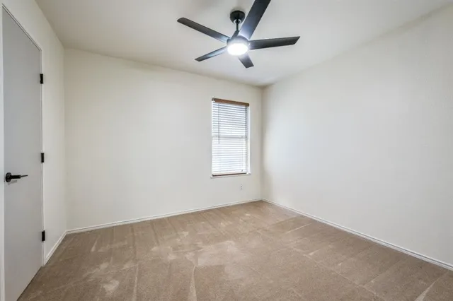 an empty room with a window and a ceiling fan