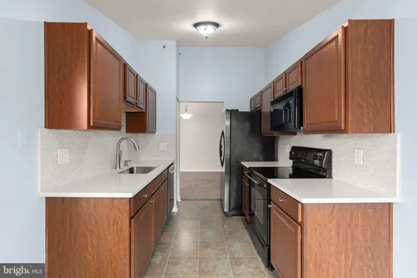 a kitchen with stainless steel appliances a sink a stove a microwave a sink a refrigerator and cabinets