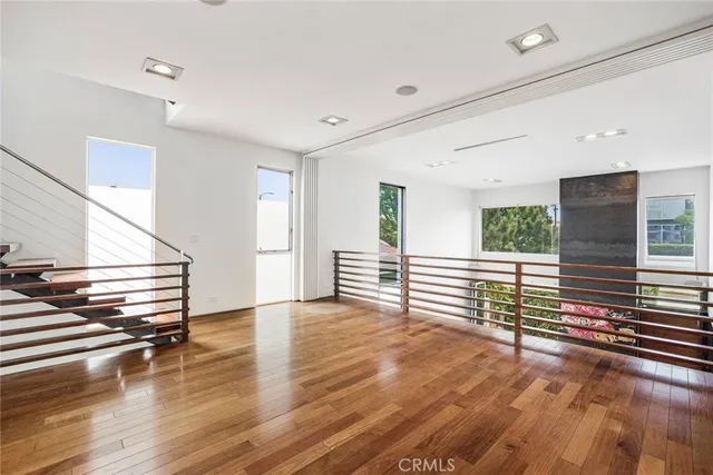 a view of empty room with wooden floor and fan