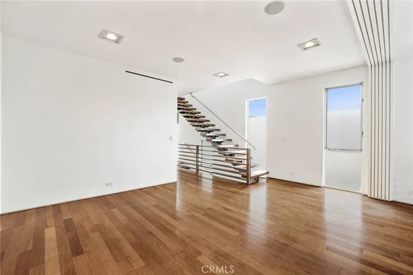 a view of an empty room with wooden floor and stairs